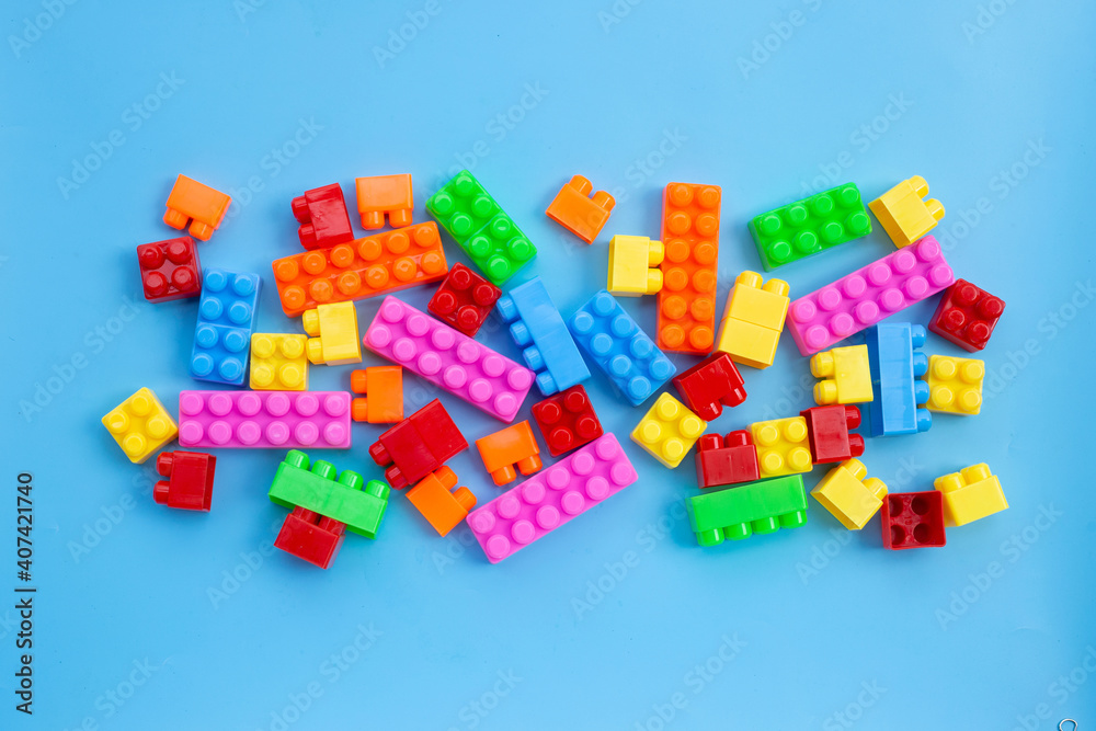 Plastic building blocks on blue background.