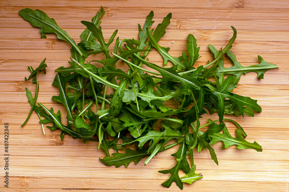 A large amount of arugula lies on a white wooden board. A large amount of arugula lies on a white wooden board.