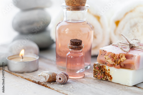 Natural organic spa products on wooden background. Essential rose oil  towel  stones. Atmosphere of relax  detention  zen. Aromatherapy. Body care  healthy lifestyle. Close up. Copy space for text.