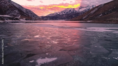 Vibrant sky glowing reflecting off ice on lake through the texture of the cracks on Deer Creek Reservoir. photo