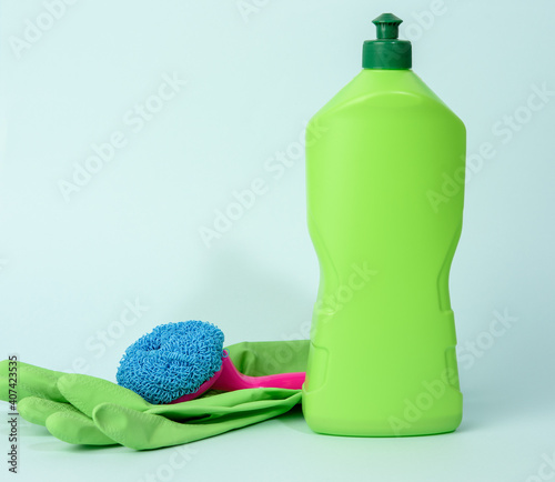 green rubber gloves for cleanin and cleaning fluid in a plastic bottle on a blue background photo