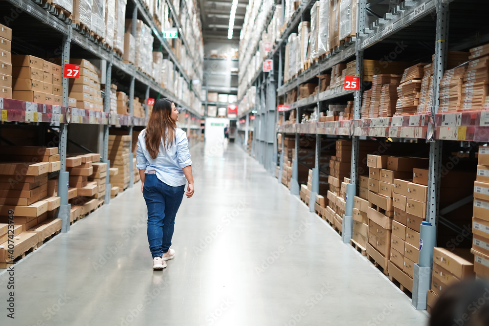 Fototapeta premium Plus size female worker inspecting box of products while working in large warehouse