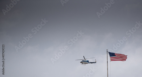 Police helicopter flying next to United States of America flag