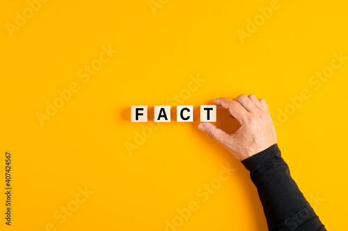 Male hand placing the wooden cubes with the word fact photo