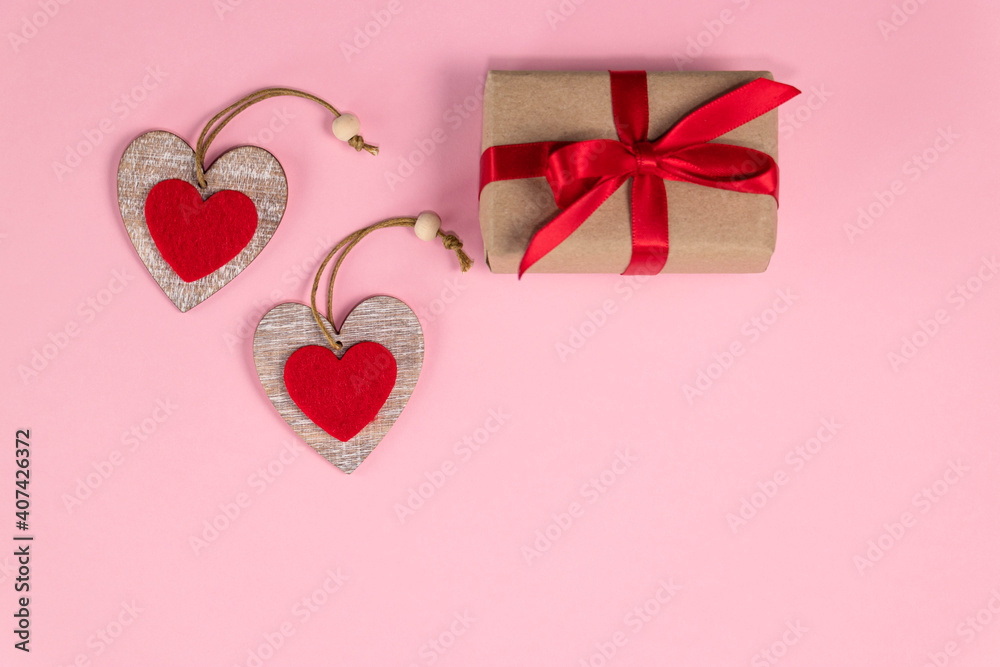 Red hearts and gift with red ribbon on pastel pink colors. Valentine's day background. Valentine's day concept. Flat lay.