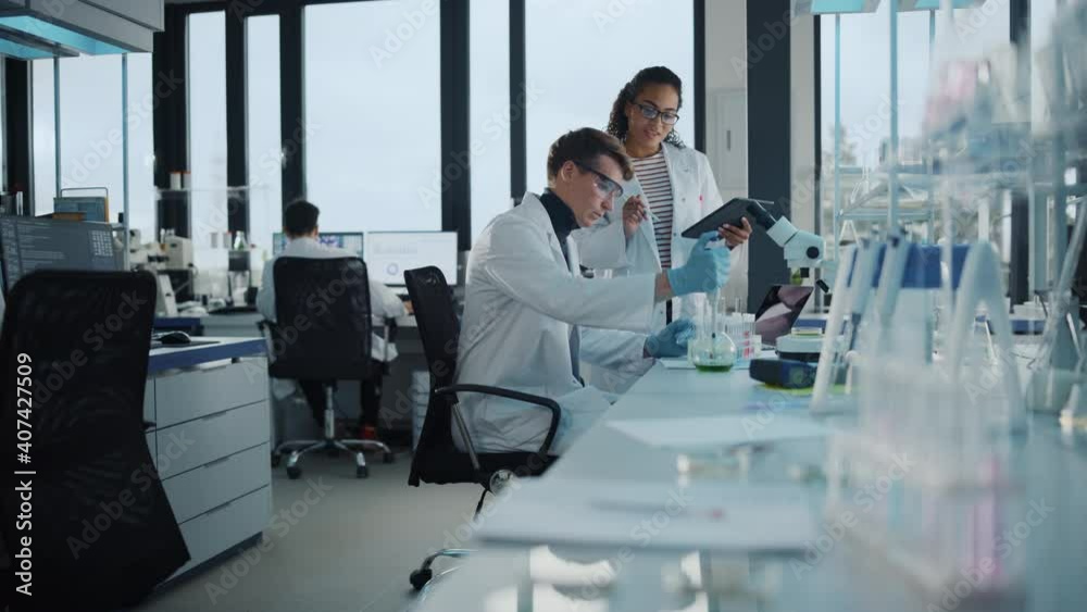 Modern Medical Research Laboratory: Portrait of Two Young Scientists Using Pipette, Digital Tablet, Doing Sample Analysis, Talking. Diverse Team of Specialists work in Advanced Bio Technology Lab