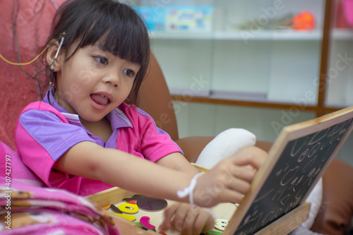 A little girl is wearing a hearing aid and is doing a neurofeedback exam. Making EEG electrodes. photo