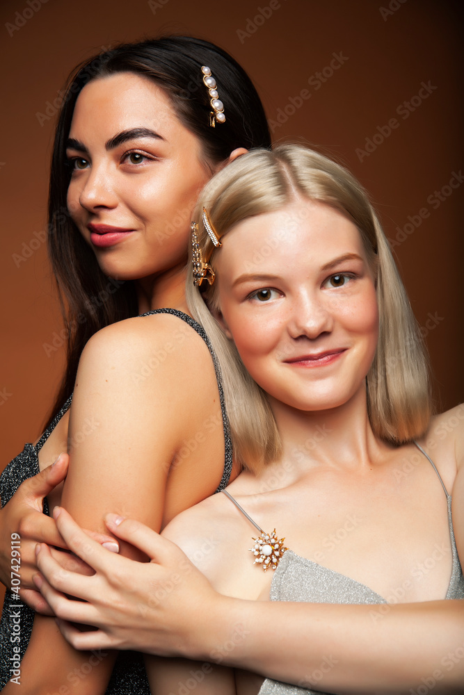 two pretty diverse girls happy posing together: blond and brunette on brown background, lifestyle people concept two pretty diverse girls happy posing together: blond and brunette on brown background, lifestyle people concept