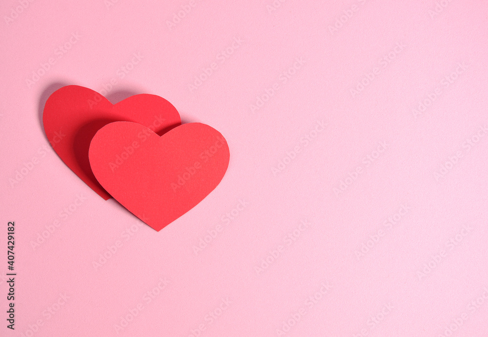 two paper hearts on pink background