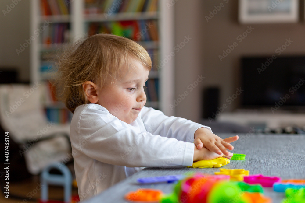 Happy smiling little boy playing with colorful clay alone. Child using plasticine and playing dough. Happy smiling little boy playing with colorful clay alone. Child using plasticine and playing dough.