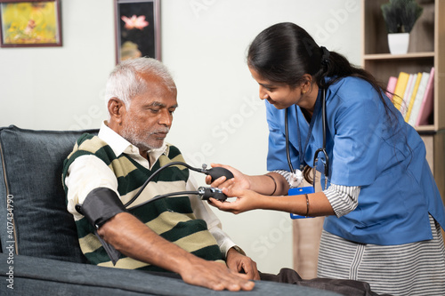 Obraz na płótnie doctor or nurse checking blood pressure or BP of patient at home - concept of elderly people routine home health care or service