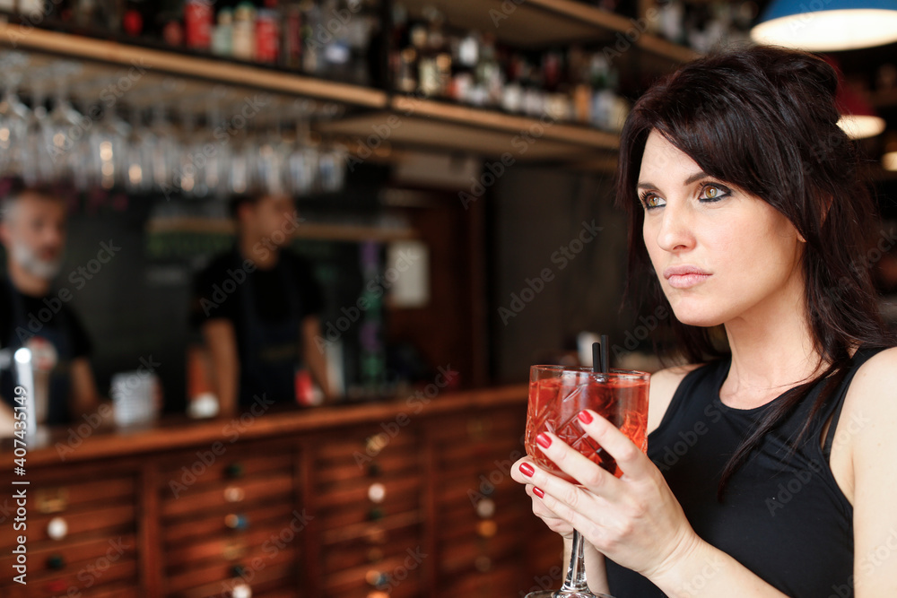 ragazza mora con gli occhi verdi ed espressione serie prende qualcosa da bere in un bar ragazza mora con gli occhi verdi ed espressione serie prende qualcosa da bere in un bar
