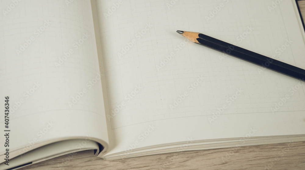 Black pencil on empty opened notebook. Wooden table background. Black pencil on empty opened notebook. Wooden table background.