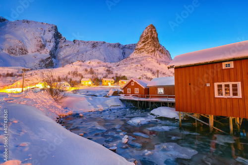 Dramatic evening cityscape of Reine town. Red rorbuers on the shore of Reinefjorden photo