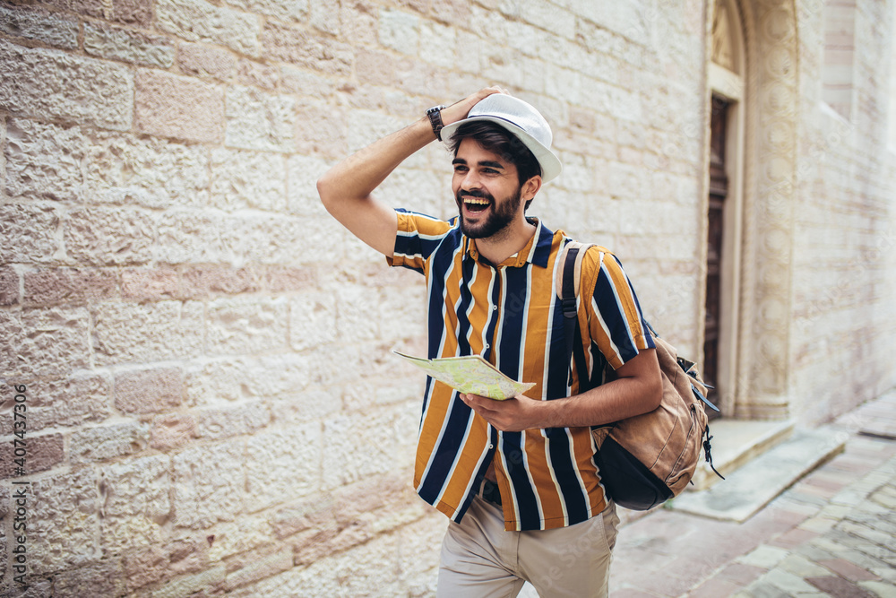 Happy tourist with backpack is making travel across city uses a map for orientation.