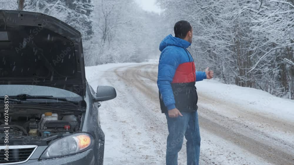 Vehicle breakdown. Young man driver catching help for her broken car, accident at empty snow road Vehicle breakdown. Young man driver catching help for her broken car, accident at empty snow road