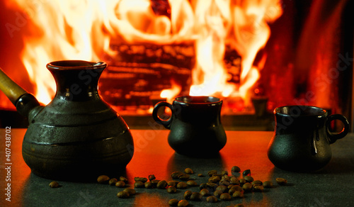 Cezve and coffee cups with coffee beans on the background of a burning fire. Preparing traditional coffee on fire
