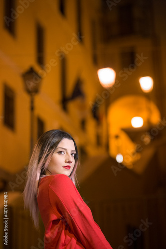 Bella ragazza con maglione rosso guarda con aria seria  in contesto urbano notturno © alex.pin