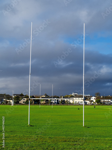 Tall goal post for Irish National sport rugby, hurling, gaelic football and camogie on a green training pitch, blue cloudy sky. Galway city in the background.