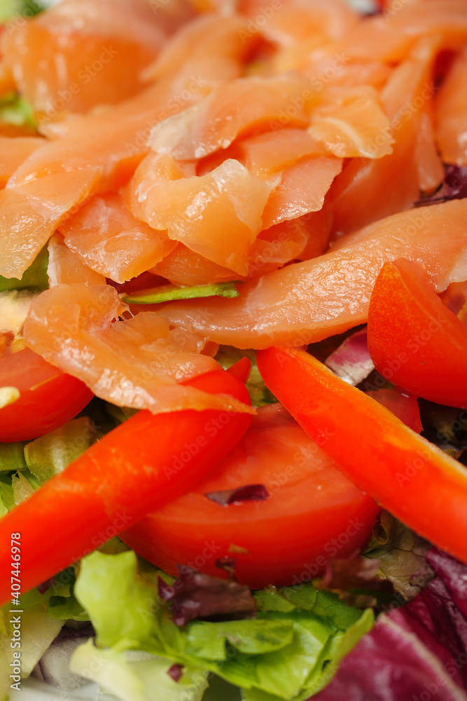 Fresh salad with smoked salmon pieces, lettuce, tomato, salad pepper and olive oil, Close up, selective focus