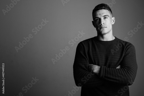 Young handsome man wearing sweater against gray background