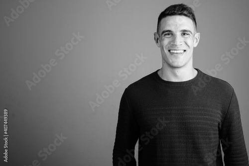 Young handsome man wearing sweater against gray background