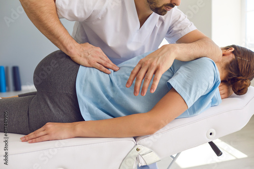 Professional chiropractor or physiotherapist helps to heal a young woman's back.