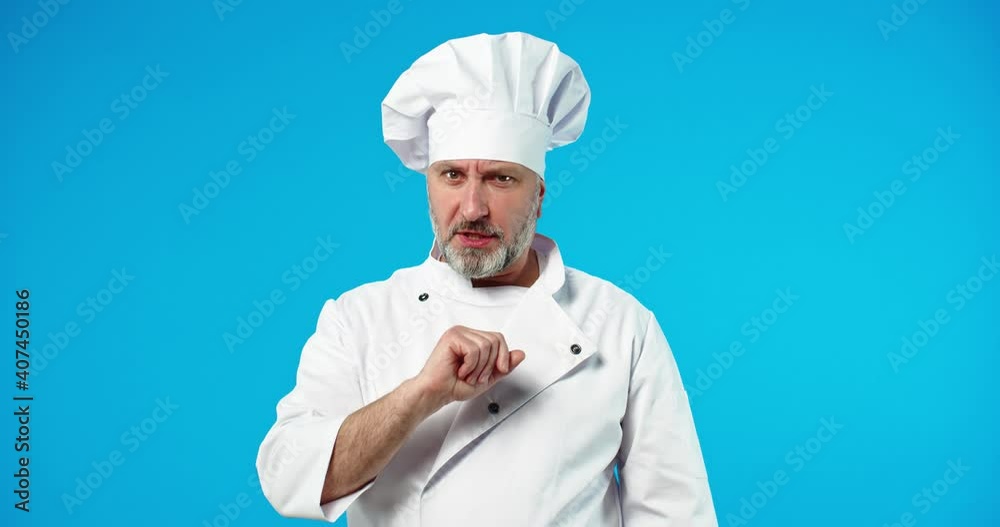 Portrait of serious unhappy Caucasian middle-aged handsome professional male chef in white uniform disagreeing, denying waving finger forbidding something looking at camera standing on blue background Portrait of serious unhappy Caucasian middle-aged handsome professional male chef in white uniform disagreeing, denying waving finger forbidding something looking at camera standing on blue background