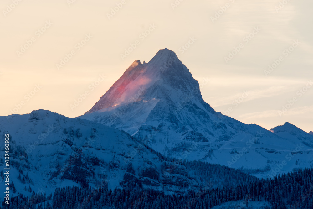 peak of Schreckhorn at dawn with red clouds in winter