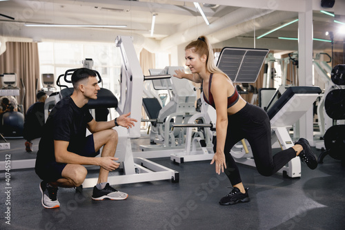 The coach checks the correctness of the exercise on the feet in the gym. Training in the gym is a small group. A man and a girl train together.