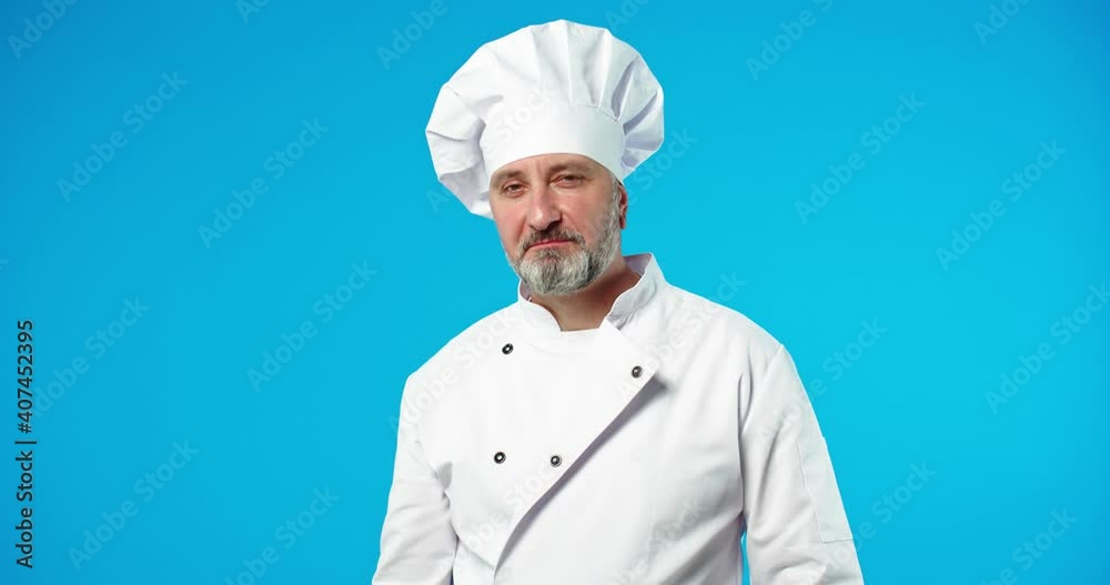 Close up portrait of Caucasian handsome middle-aged joyful male cook in white chef uniform standing isolated on blue wall with satisfied happy face expression making kiss gesture, delicious meal Close up portrait of Caucasian handsome middle-aged joyful male cook in white chef uniform standing isolated on blue wall with satisfied happy face expression making kiss gesture, delicious meal