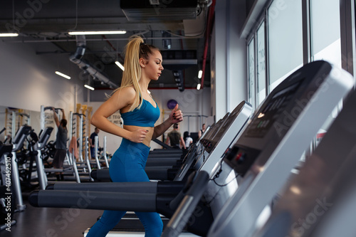 Young woman running on treadmill. Beautiful young woman in gym. © zorandim75