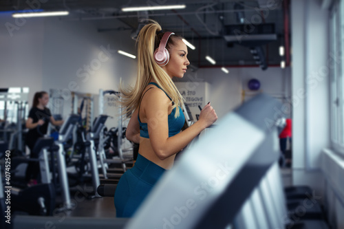 Young woman running on treadmill. Beautiful young woman in gym.