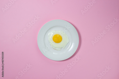 Scrambled eggs on a pink background. Fried eggs on a white plate. Tasty breakfast.