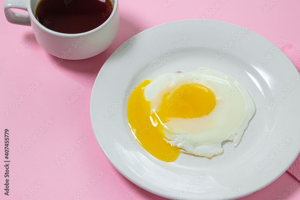 Scrambled eggs on a pink background. Fried eggs on a white plate. Delicious breakfast with a cup of coffee. Scrambled eggs on a pink background. Fried eggs on a white plate. Delicious breakfast with a cup of coffee.