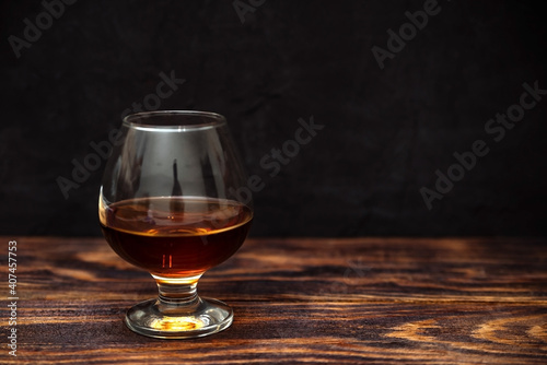 glass of alcoholic drink on a black background, cognac on a dark wooden background