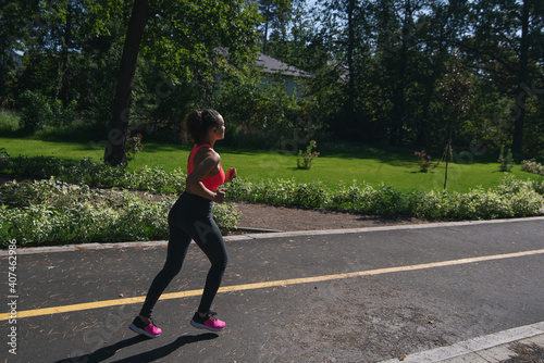 Side view of a woman runner jogging on a running way in the park. Fitness outdoor concept. Cardio training