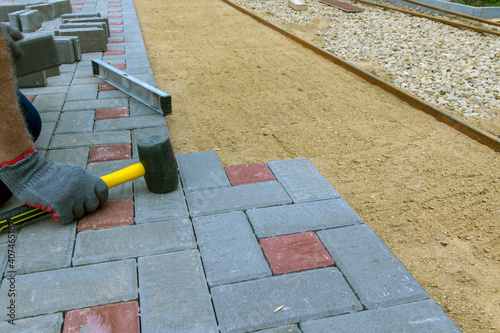 Laying paving stones on a garden path. Laying gray concrete paving slabs in the yard on a flat sandy foundation.