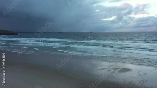 Aerial view over a mirroring beach and waves crashing the coast of North Spain - tracking, pan, drone shot photo