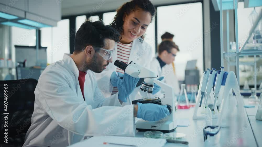 Modern Medical Research Laboratory: Portrait of Latin and Black Young Scientists Using Microscope, Digital Tablet, Doing Sample Analysis, Talking. Diverse Team of Specialists work in Advanced Lab