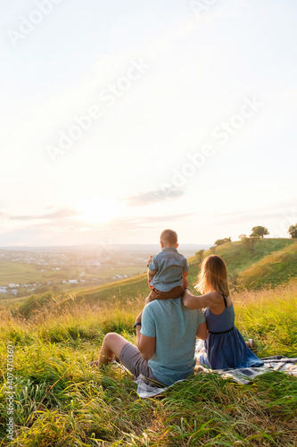 Rear view of joyful happy family sitting together at outdoor looking on sunset