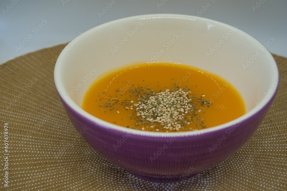 pumpkin cream with sesame and spices into a violet bowl in natural fiber background. Healthy food concept pumpkin cream with sesame and spices into a violet bowl in natural fiber background. Healthy food concept