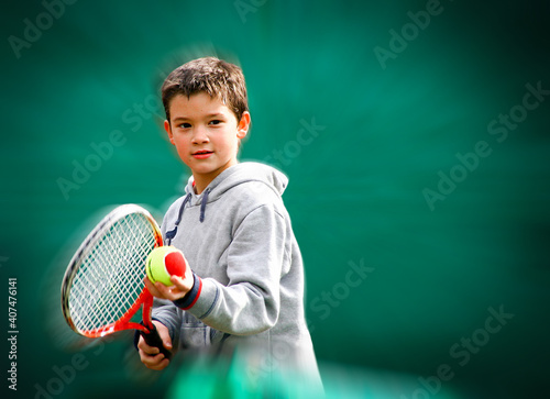 Little boy tennis player on a blurred and zooming green background