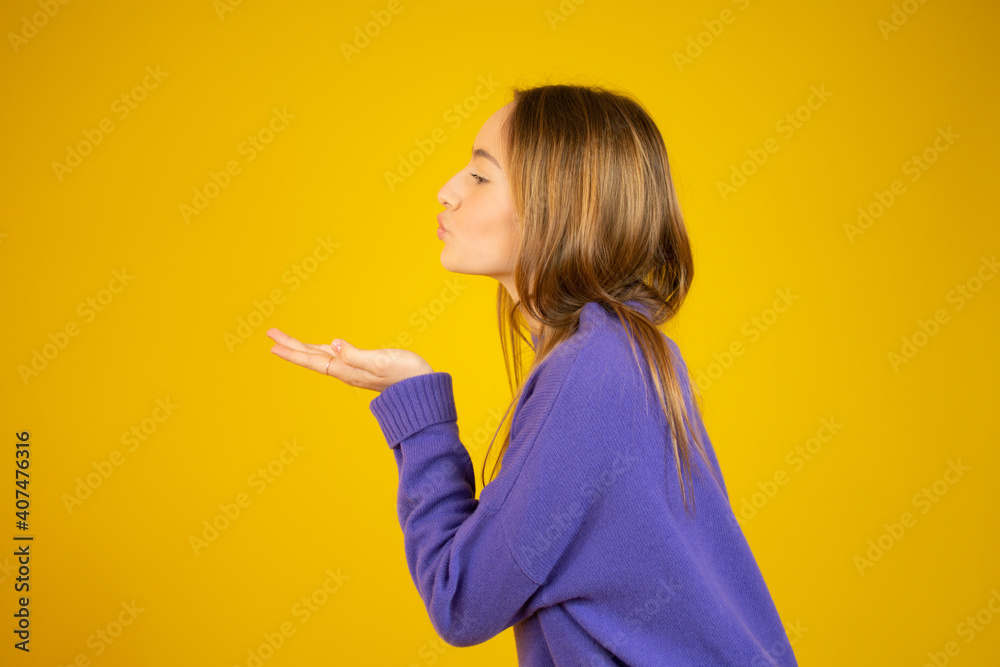 Side profile photo of girl sending air kiss with closed eyes isolated on yellow color background Side profile photo of girl sending air kiss with closed eyes isolated on yellow color background
