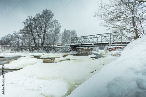 Waterfall in winter, strong current, frozen ice
  and trees in other. landscape photography
  Frost, ice, cold concept. Old town in Helsinki photo