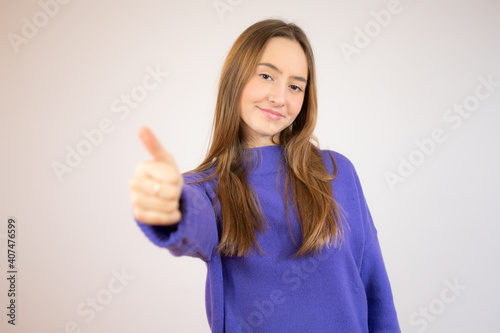 Portrait of a happy young beautiful girl showing okay gesture and winking isolated over white background