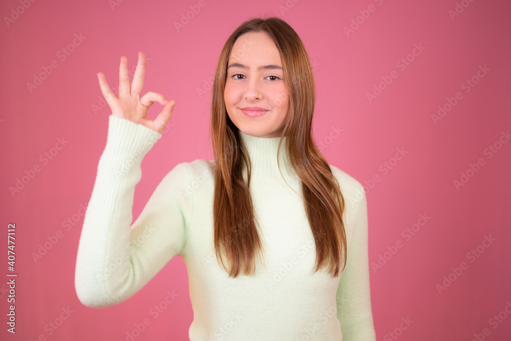 Portrait of a happy young girl showing okay gesture and winking isolated over pink background Portrait of a happy young girl showing okay gesture and winking isolated over pink background