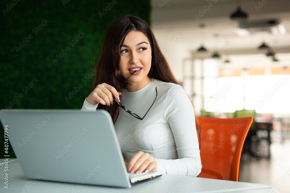 Naklejka premium beautiful young woman in glasses at the table with laptop in the office