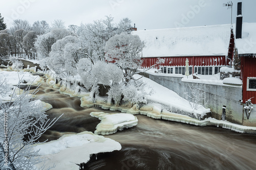 Waterfall in winter, strong current, frozen ice
  and trees in other. landscape photography
  Frost, ice, cold concept. Old town in Helsinki photo