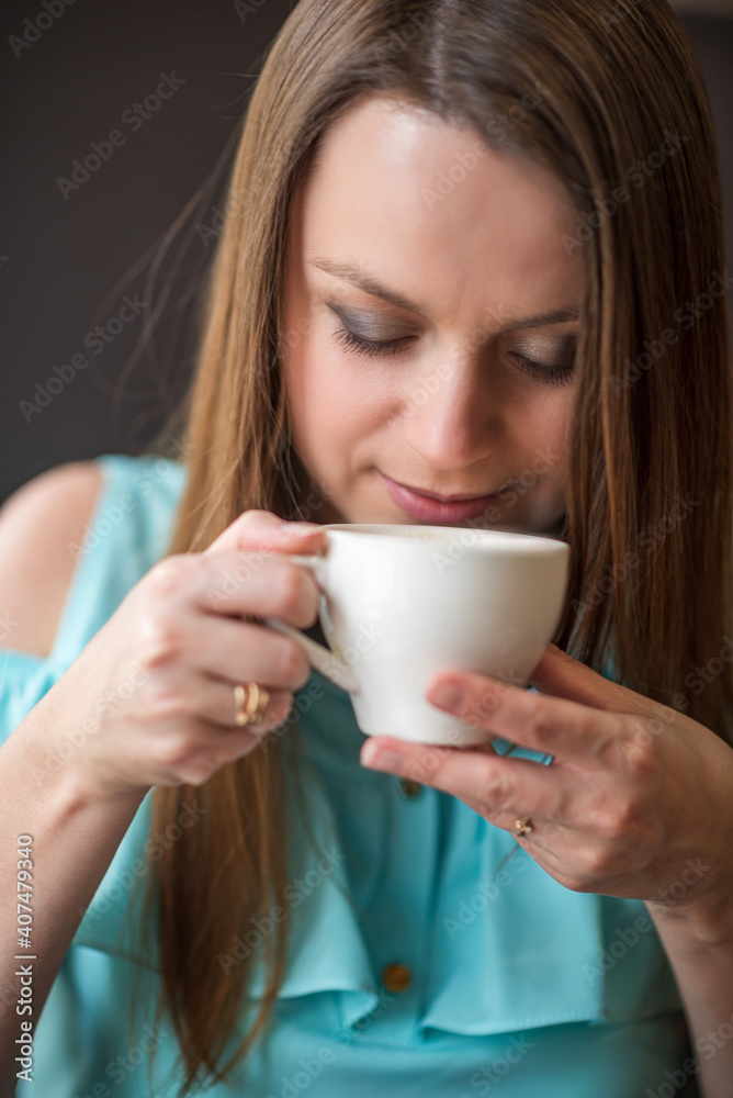 Young beautiful girl with brown hair drinks coffee in a cafe. Young beautiful girl with brown hair drinks coffee in a cafe.